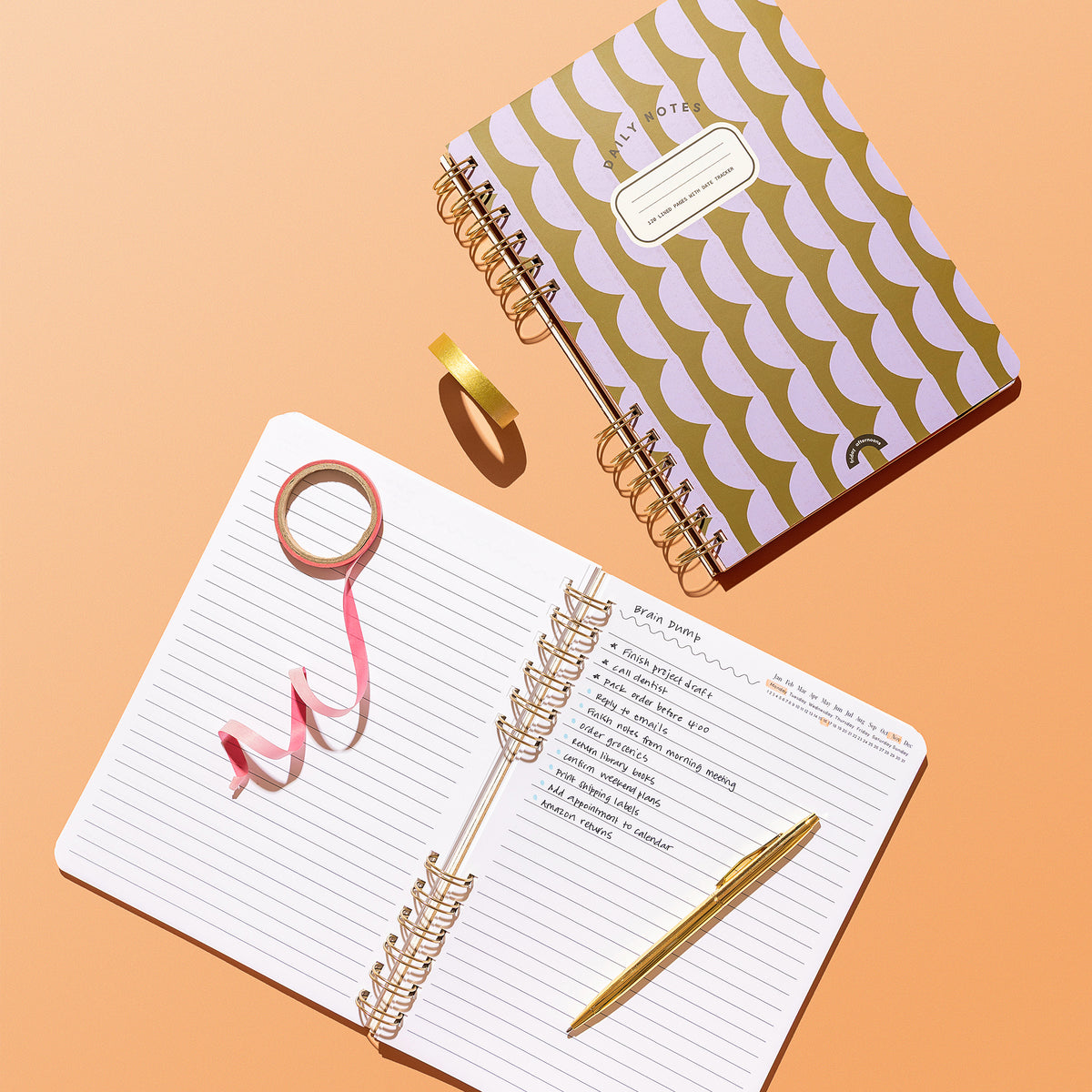 Forest and Lavender Half Moons notebook beside open lined pages with handwritten notes and a gold pen.