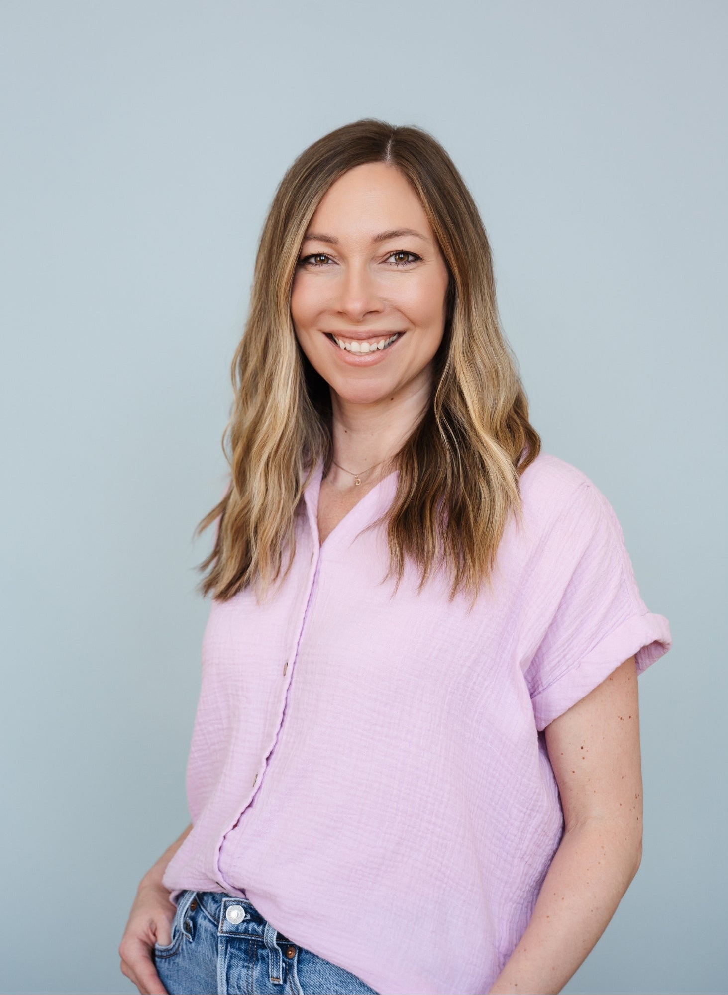 Woman wearing a light purple shirt against a plain background