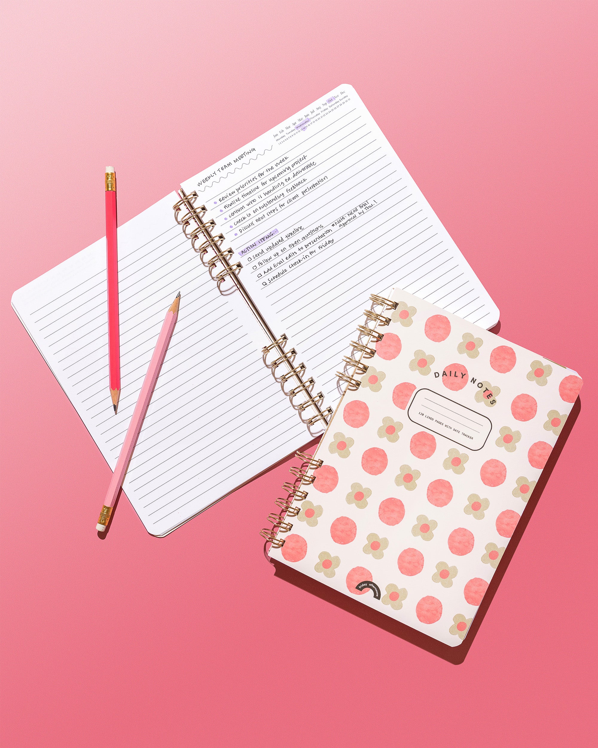 Sage Petals Daily Notes notebook beside open lined pages with handwritten meeting notes and pink pencils on a pink background.
