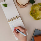 Person writing in the Mini Memo Notebook, shown open on a desk.