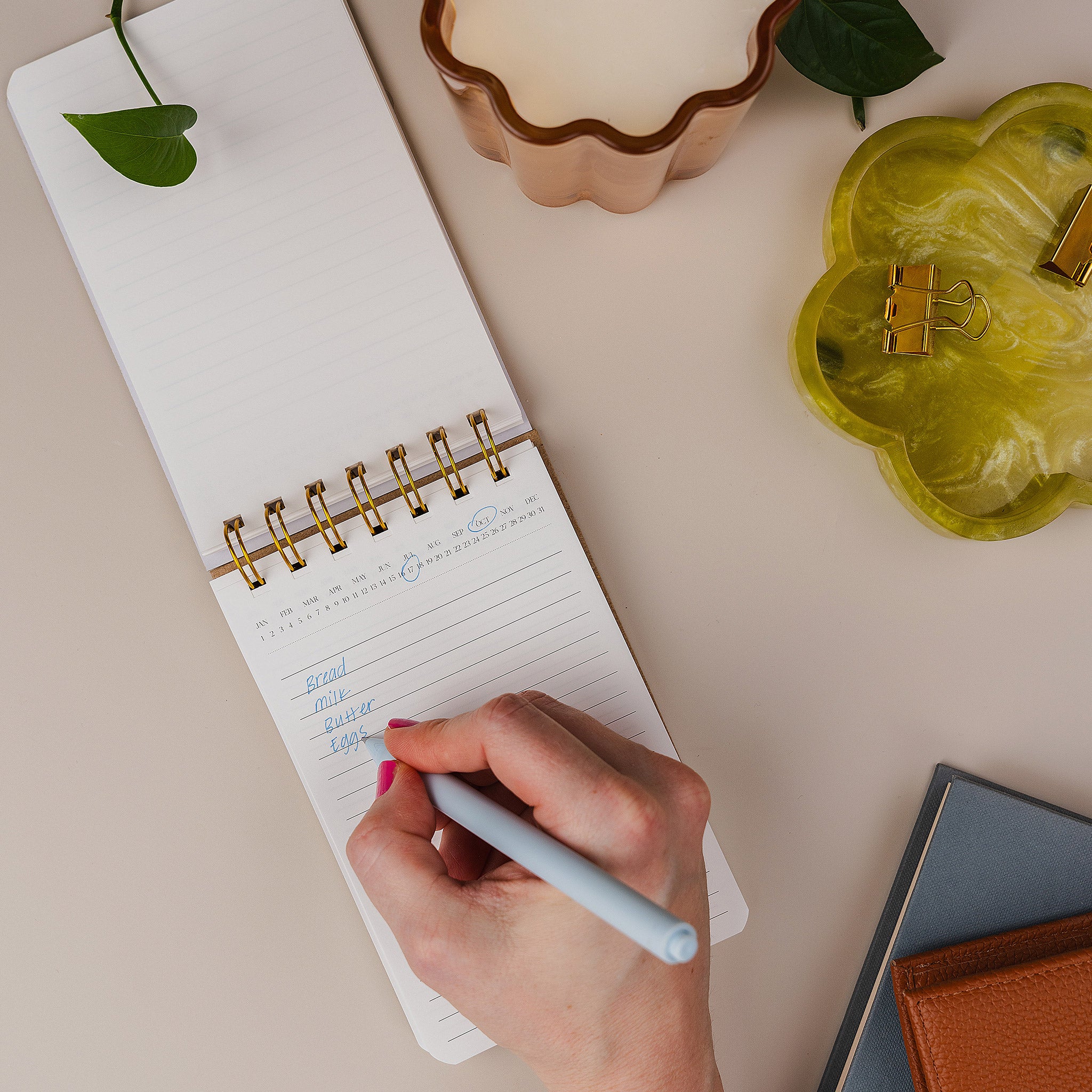 Person writing in the Mini Memo Notebook, shown open on a desk.