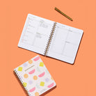 Bright Shapes Quarterly Plans 90-Day Planner with colorful geometric cover shown beside an open daily planning page and gold pen on an orange background.