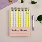 Lima Wavy Stripes Workday Planner — top-spiral daily planner for work with pink and green patterned cover on desk.