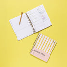 Lima Wavy Stripes Quarterly Plans 90-Day Planner with yellow wavy stripe cover shown beside an open daily planning page and gold pen on a bright yellow background.