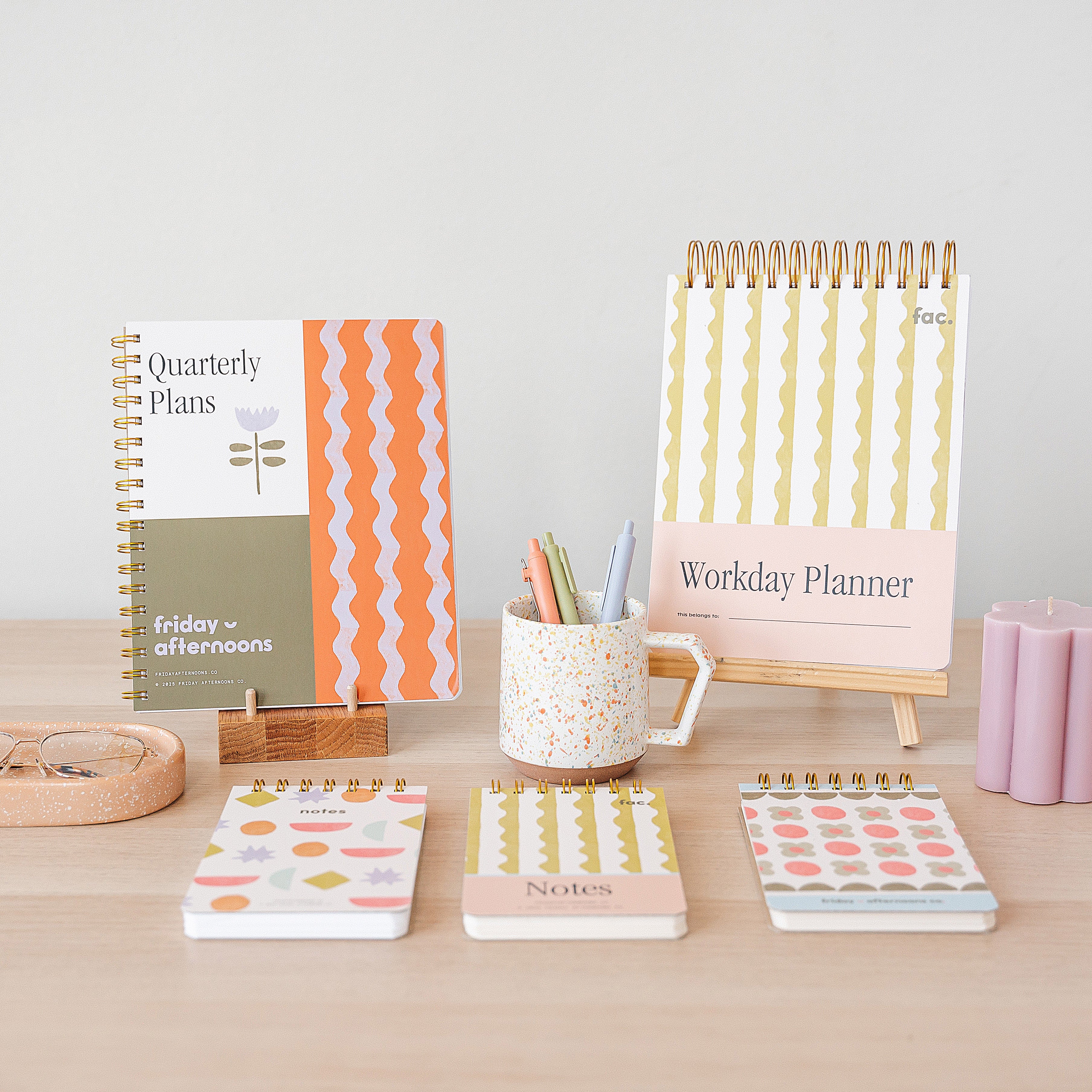 Friday Afternoons Co. desk display featuring the Quarterly Plans 90-Day Planner, the Workday Planner, and Mini Memo notebooks in assorted patterned covers.