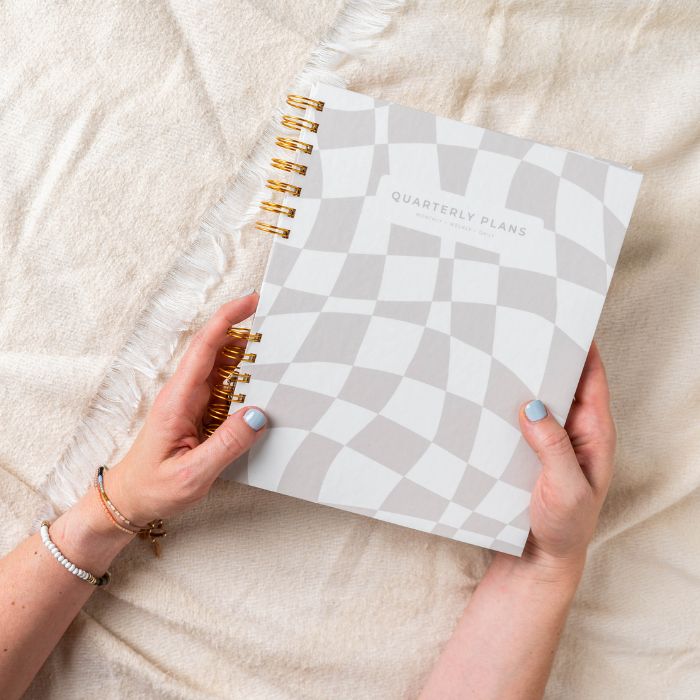 woman holding friday afternoons quarterly plans 90 day planner taupe beige creamy checker color design