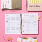 Quarterly Plans 90-day planner with monthly planning pages, quarterly goal planning spread, and colorful cover designs on a pink background.