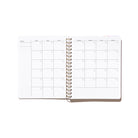 Quarterly Plans monthly calendar spread with undated month grid, sidebar notes area, and gold spiral binding.