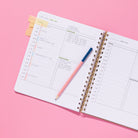 Quarterly Plans daily planning pages with hourly schedule, work checklist, personal checklist, sticky tabs, and pink pencil on a pink background.