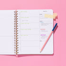 Quarterly Plans weekly planning page with weekly focus, priorities, checklist, notes section, sticky tabs, and pink pencil on a pink background.