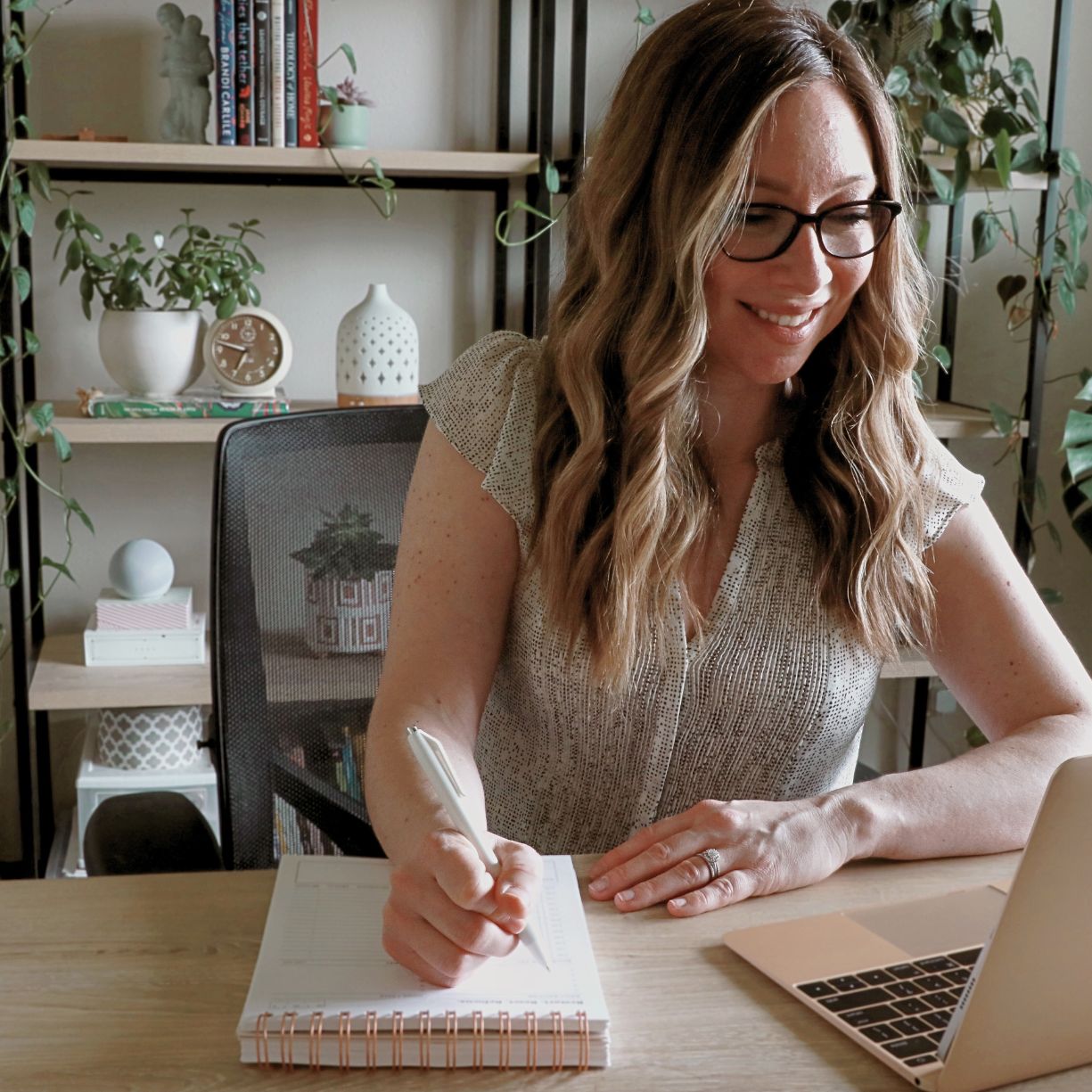 woman working at desk with smile writing in her friday afternoons planner