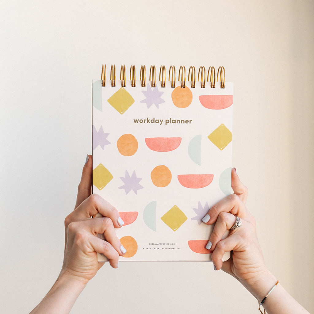 Hands holding the Workday Planner with a colorful geometric cover from Friday Afternoons Co.